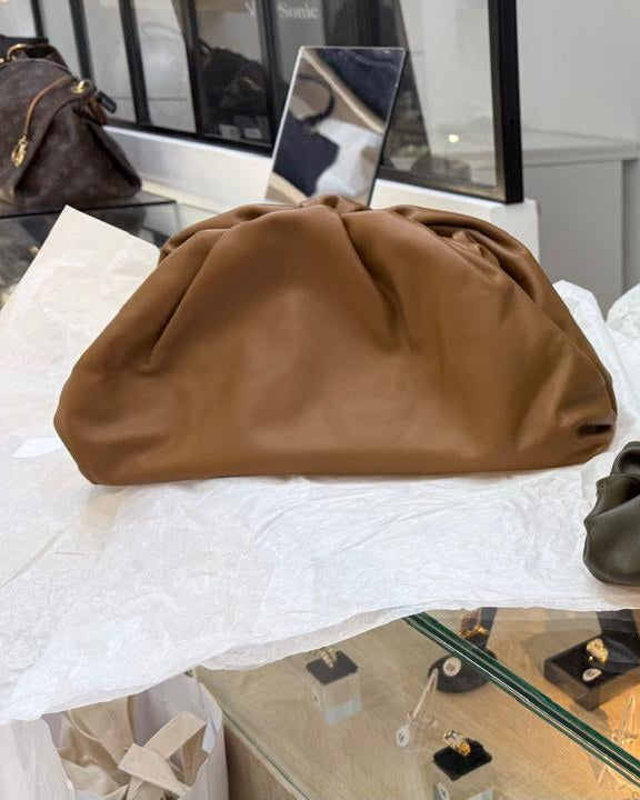 Bolsa de couro caramelo apoiada sobre papel de seda, no balcão de vidro de uma loja